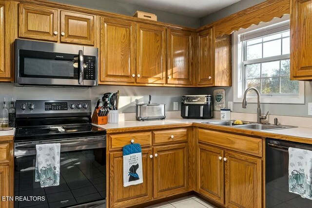 kitchen featuring sink, light tile patterned floors, and black appliances