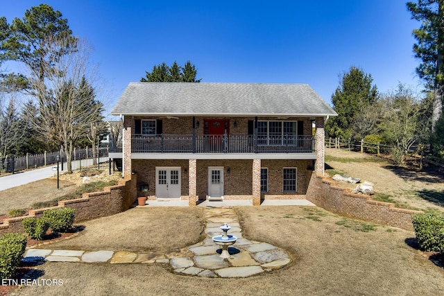 view of front of property with french doors, brick siding, a patio, and fence