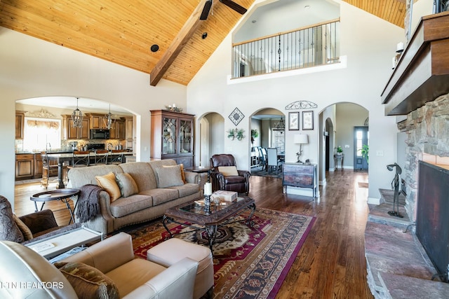 living room with a fireplace, wood ceiling, dark wood-type flooring, and vaulted ceiling with beams