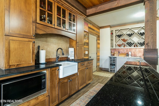 kitchen with sink, dark wood-type flooring, dark stone countertops, beverage cooler, and beamed ceiling