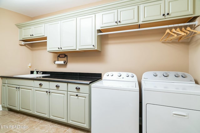 washroom with cabinets, washer and dryer, and sink