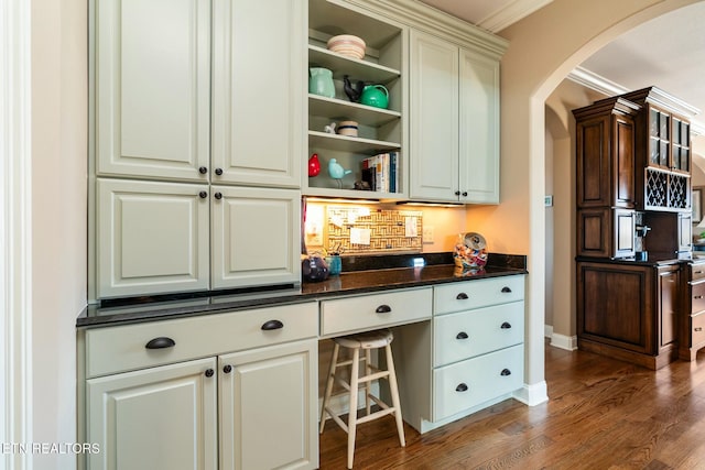 bar featuring crown molding, dark hardwood / wood-style flooring, and dark stone countertops