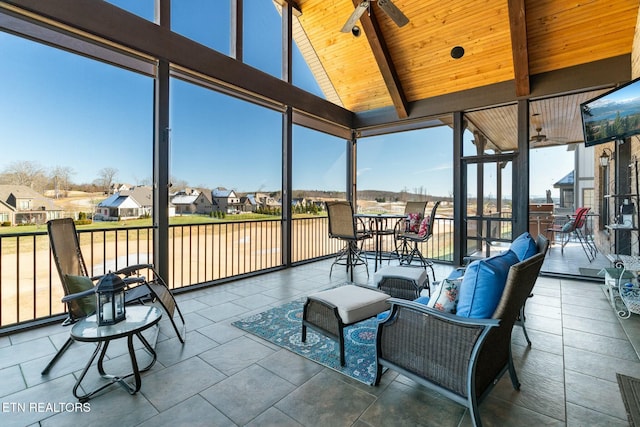 sunroom with lofted ceiling with beams, ceiling fan, and wood ceiling