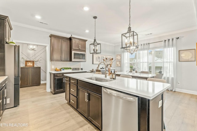 kitchen featuring dark brown cabinetry, stainless steel appliances, a kitchen island with sink, and sink