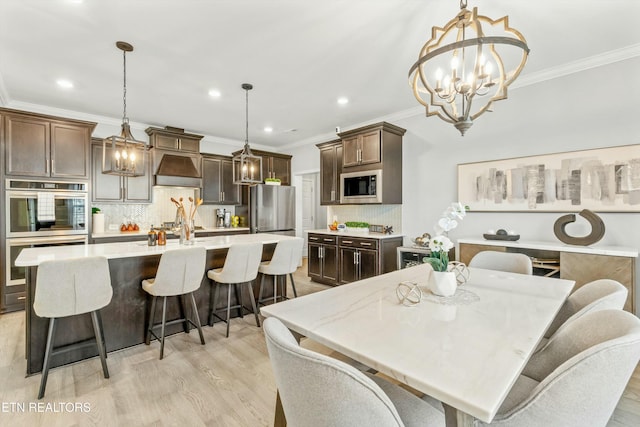 dining area with crown molding, a notable chandelier, and light wood-type flooring