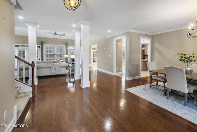 interior space with dark hardwood / wood-style floors, ornate columns, and ornamental molding