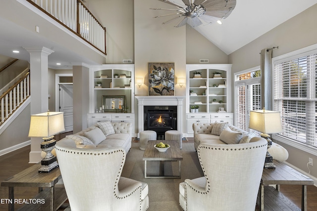 living room with ceiling fan, high vaulted ceiling, dark hardwood / wood-style floors, decorative columns, and crown molding