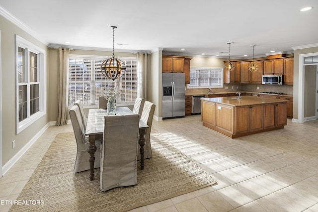 tiled dining space featuring a notable chandelier, a healthy amount of sunlight, sink, and crown molding