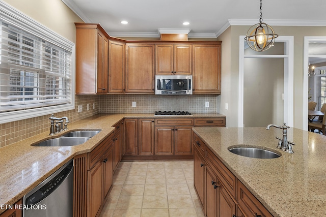 kitchen with light stone counters, sink, stainless steel appliances, and an inviting chandelier