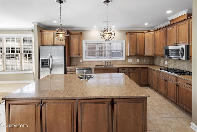 kitchen featuring light stone countertops, appliances with stainless steel finishes, sink, pendant lighting, and a center island