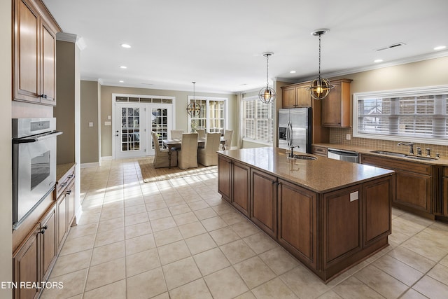 kitchen featuring pendant lighting, sink, stainless steel appliances, and an island with sink