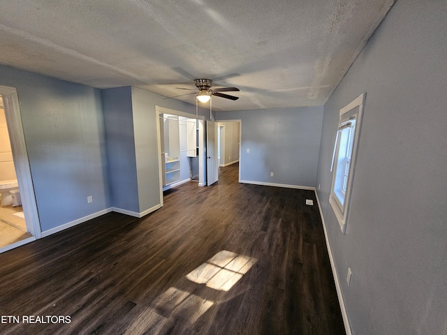 unfurnished bedroom with a textured ceiling, ensuite bathroom, ceiling fan, and dark wood-type flooring