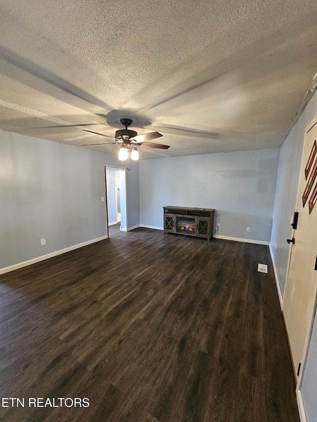 unfurnished living room with ceiling fan, dark wood-type flooring, and a textured ceiling