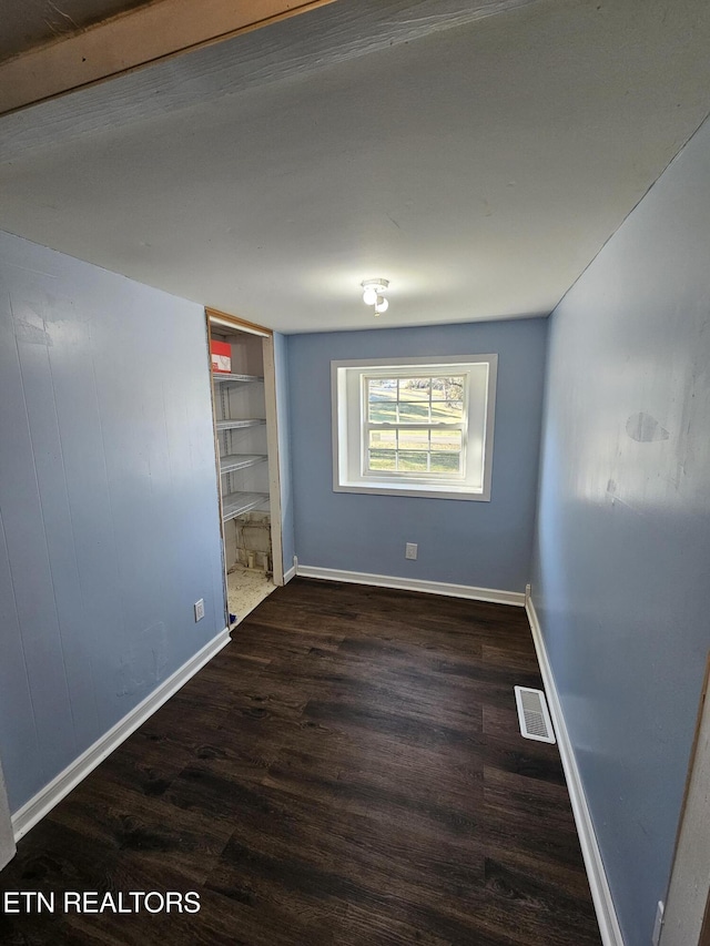 unfurnished room featuring built in shelves and dark hardwood / wood-style flooring