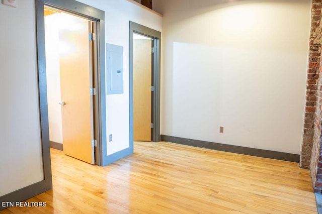 empty room featuring electric panel and light hardwood / wood-style floors