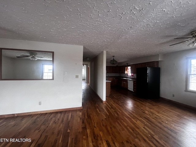 kitchen featuring dishwasher, black refrigerator, dark wood-type flooring, and a textured ceiling