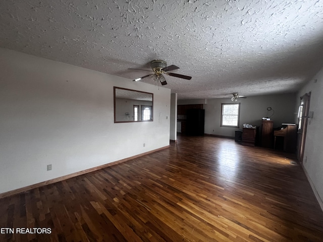 unfurnished living room featuring a textured ceiling, ceiling fan, and dark wood-type flooring