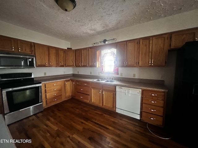 kitchen with a textured ceiling, stainless steel appliances, dark wood-type flooring, and sink