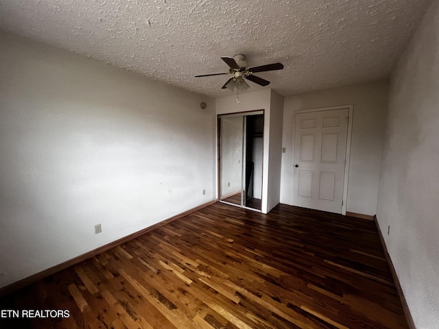 empty room with ceiling fan, dark wood-type flooring, and a textured ceiling