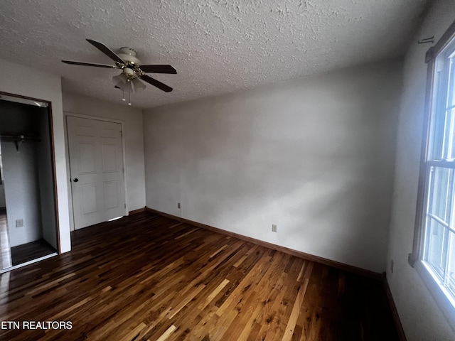 unfurnished bedroom with ceiling fan, dark hardwood / wood-style floors, a textured ceiling, and a closet