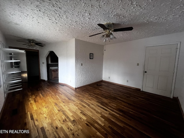 unfurnished living room featuring ceiling fan, dark hardwood / wood-style flooring, and a textured ceiling