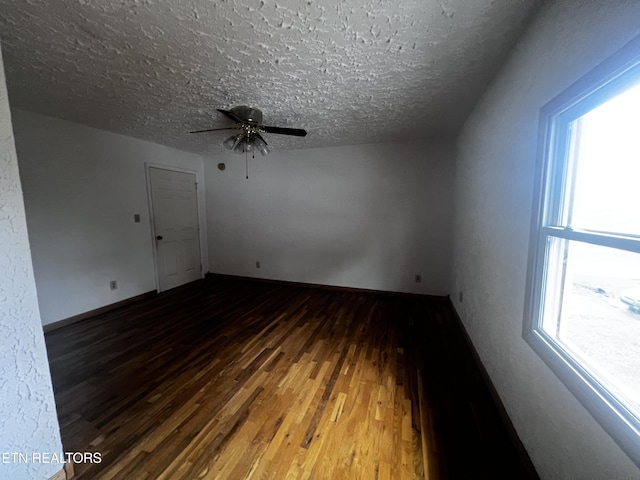 empty room with hardwood / wood-style flooring, plenty of natural light, and a textured ceiling