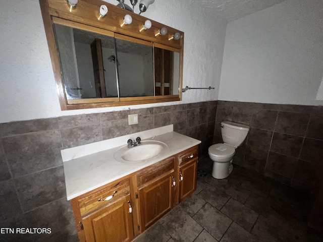 bathroom with vanity, tile walls, and toilet