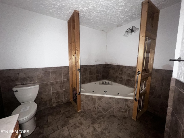 bathroom featuring toilet, a tub, a textured ceiling, and tile walls