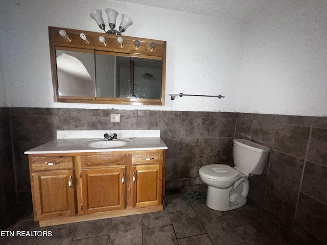 bathroom featuring tile patterned flooring, vanity, tile walls, and toilet