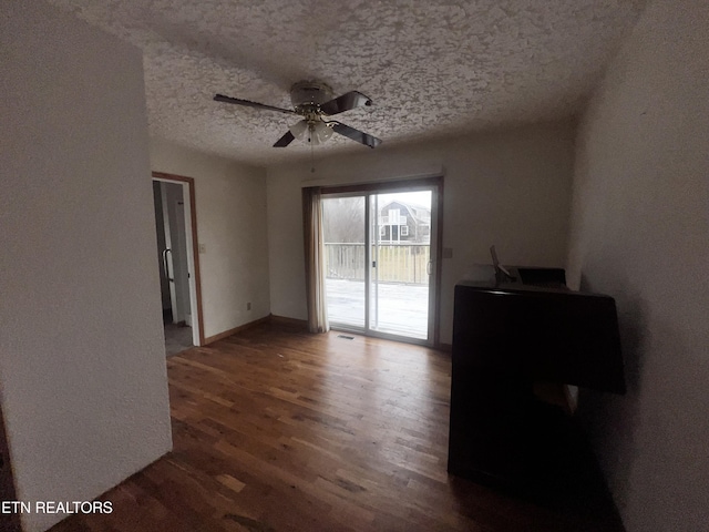 unfurnished room with a textured ceiling, dark hardwood / wood-style floors, and ceiling fan