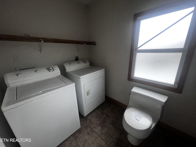 clothes washing area featuring washer and clothes dryer and dark tile patterned flooring