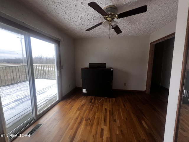 unfurnished living room with a textured ceiling, dark hardwood / wood-style flooring, and ceiling fan