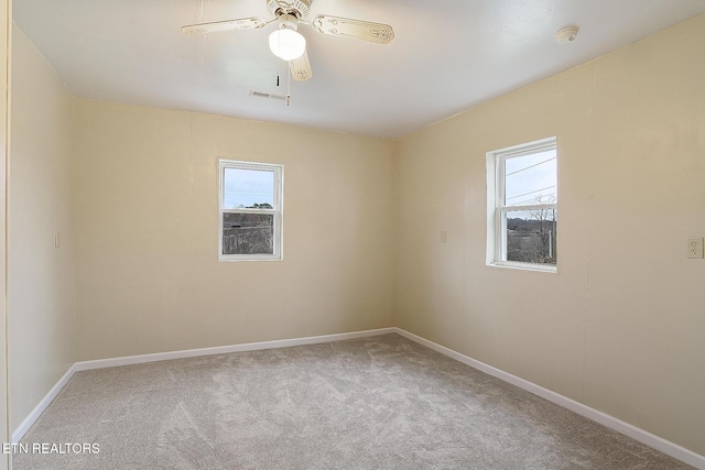 carpeted spare room with a wealth of natural light and ceiling fan