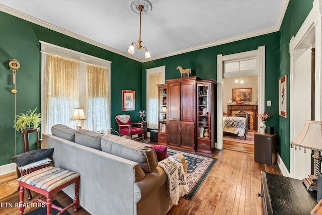 living room with an inviting chandelier, light hardwood / wood-style flooring, and ornamental molding