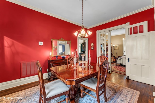 dining room featuring crown molding, dark hardwood / wood-style floors, and a chandelier