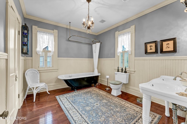 bathroom with toilet, wood-type flooring, a tub, ornamental molding, and a notable chandelier