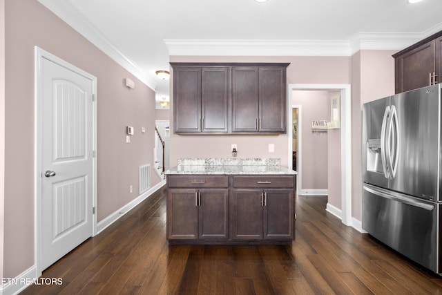 kitchen with stainless steel fridge, light stone counters, dark brown cabinets, and crown molding