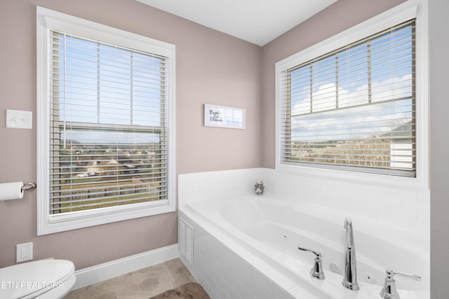 bathroom with tiled bath, toilet, and a wealth of natural light