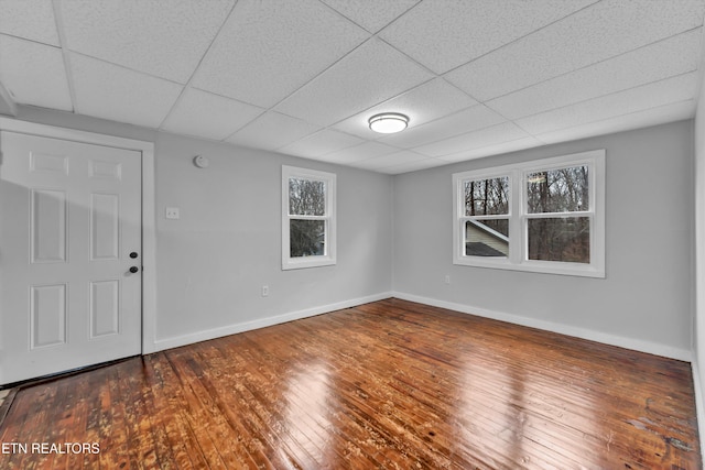 interior space with a paneled ceiling and dark hardwood / wood-style floors