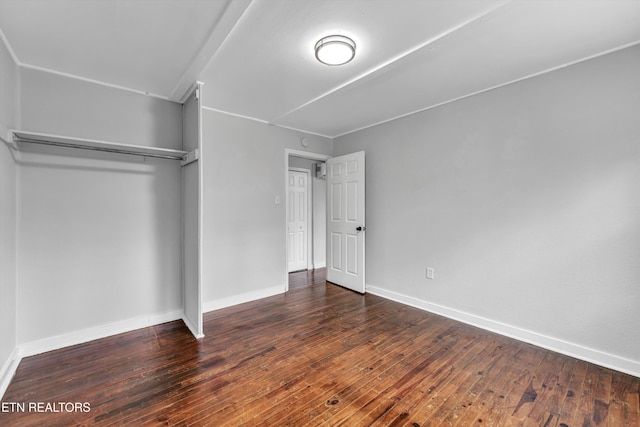 unfurnished bedroom featuring dark wood-type flooring and a closet