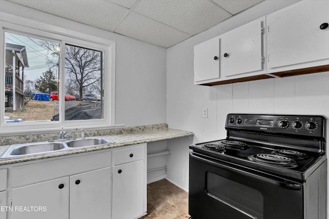 kitchen with black / electric stove, sink, white cabinets, and a drop ceiling