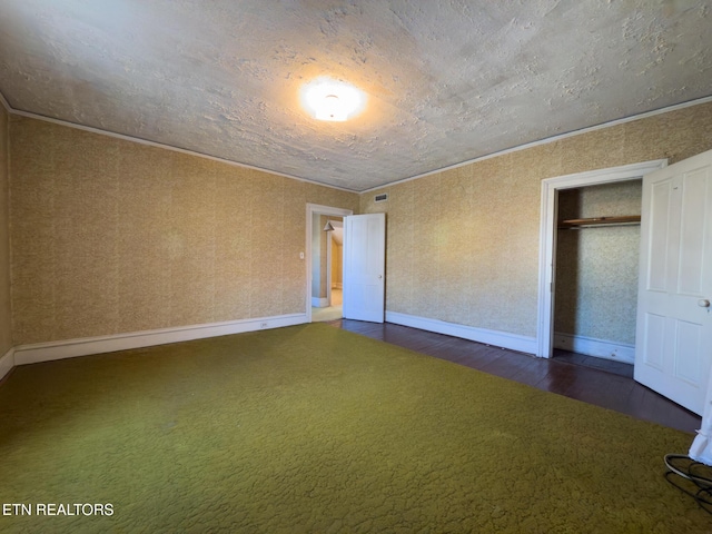 unfurnished bedroom featuring dark wood-style flooring, a closet, baseboards, and dark colored carpet