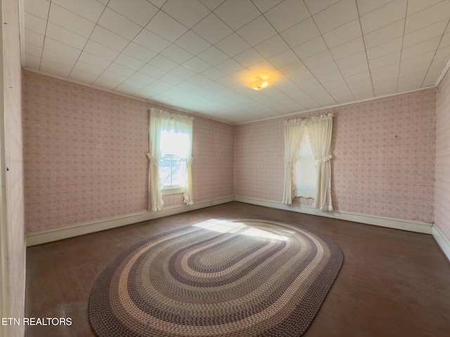 spare room with dark wood-style floors, ornamental molding, baseboards, and wallpapered walls