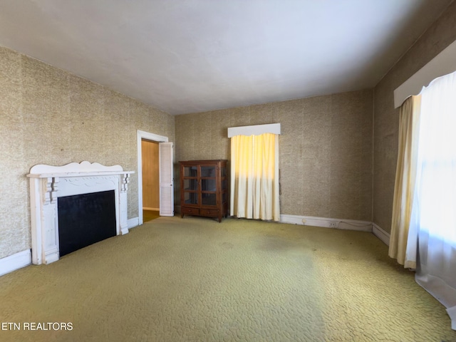 unfurnished living room featuring carpet floors, a high end fireplace, and baseboards