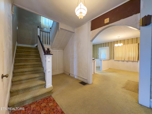 stairs featuring wallpapered walls, visible vents, arched walkways, and carpet flooring