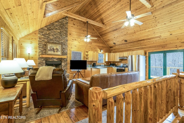 living room with light hardwood / wood-style floors, a stone fireplace, wooden ceiling, and high vaulted ceiling