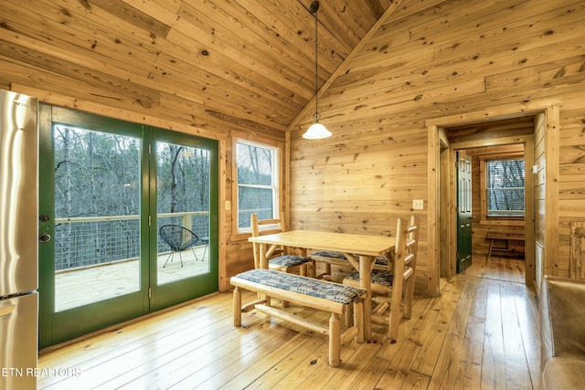 dining area with light hardwood / wood-style flooring, wooden walls, and wood ceiling