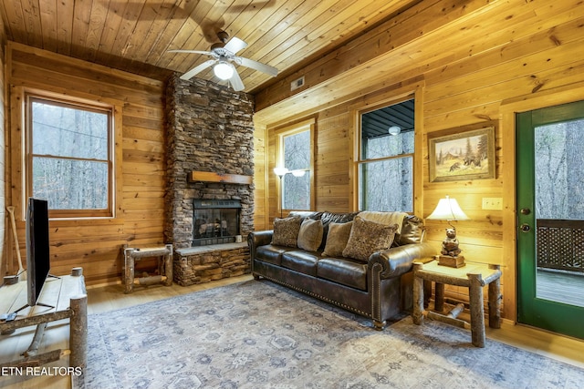 living room featuring ceiling fan, wood walls, a fireplace, wood ceiling, and hardwood / wood-style flooring