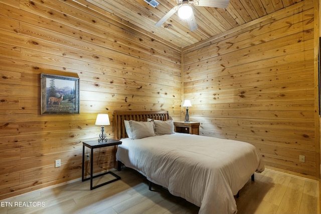 bedroom with light wood-type flooring, ceiling fan, wood walls, and wood ceiling