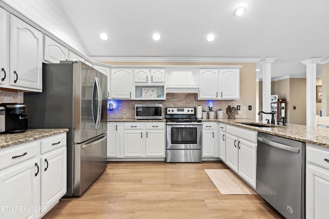 kitchen featuring appliances with stainless steel finishes, backsplash, vaulted ceiling, sink, and white cabinets